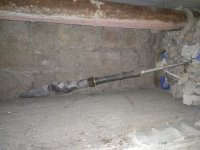 Pomieszczenie piwniczne ze znalezionym zabetonowanym w ścianie pociskiem przeciwpancernym z ładunkiem kumulacyjnym.