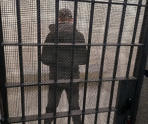 mężczyzna stojący tyłem za kratkami policyjnej celi