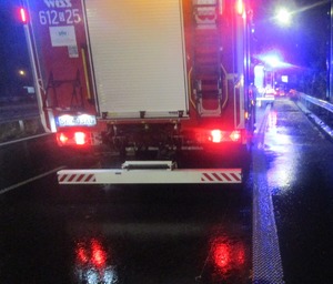 Tył pojazdu straży pożarnej zabezpieczający miejsce wypadku. w tle niebieskie lampy błyskowe pojazdów uprzywilejowanych.